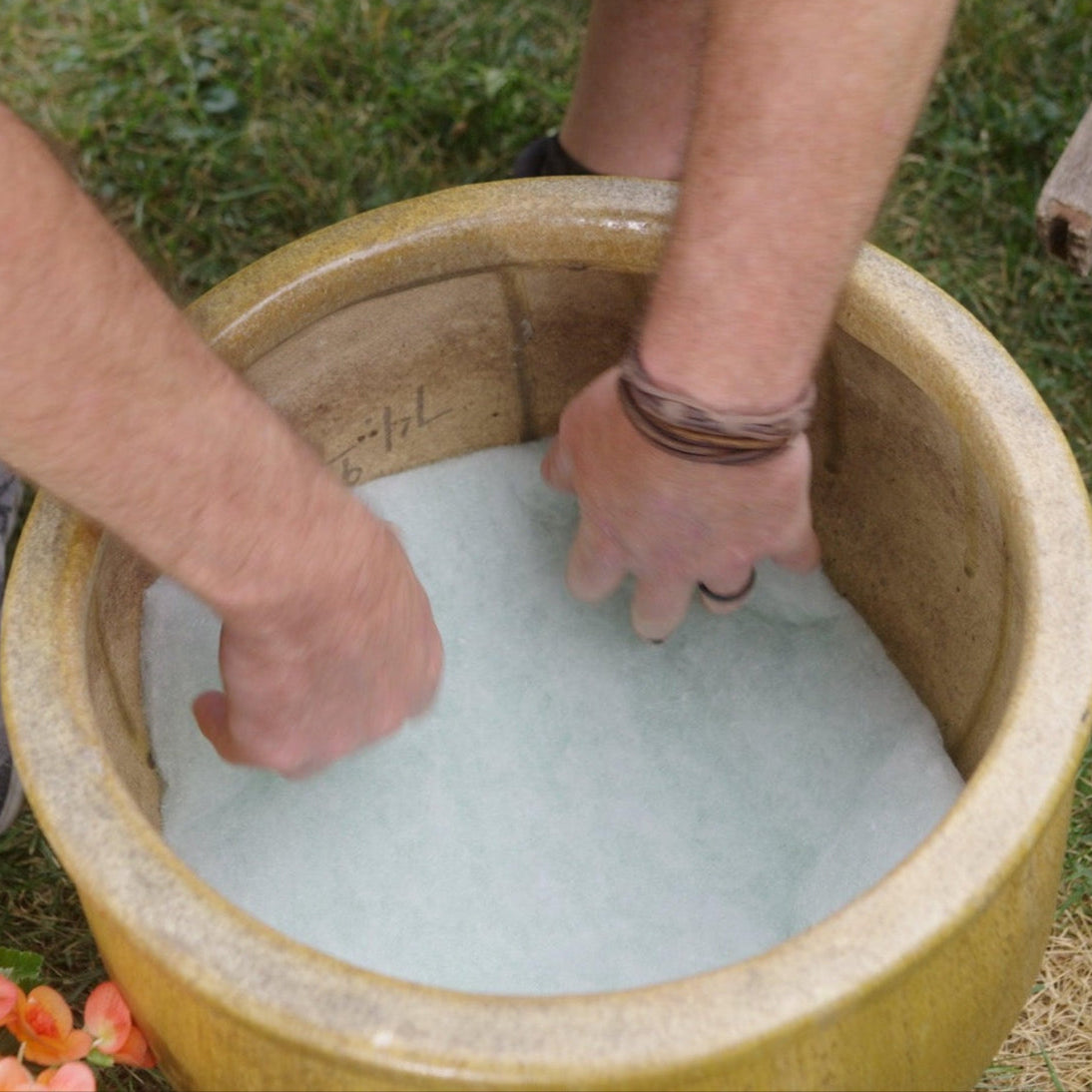 Person placing Better Than Rocks drainage insert into a planter pot to improve drainage and reduce weight before planting flowers.